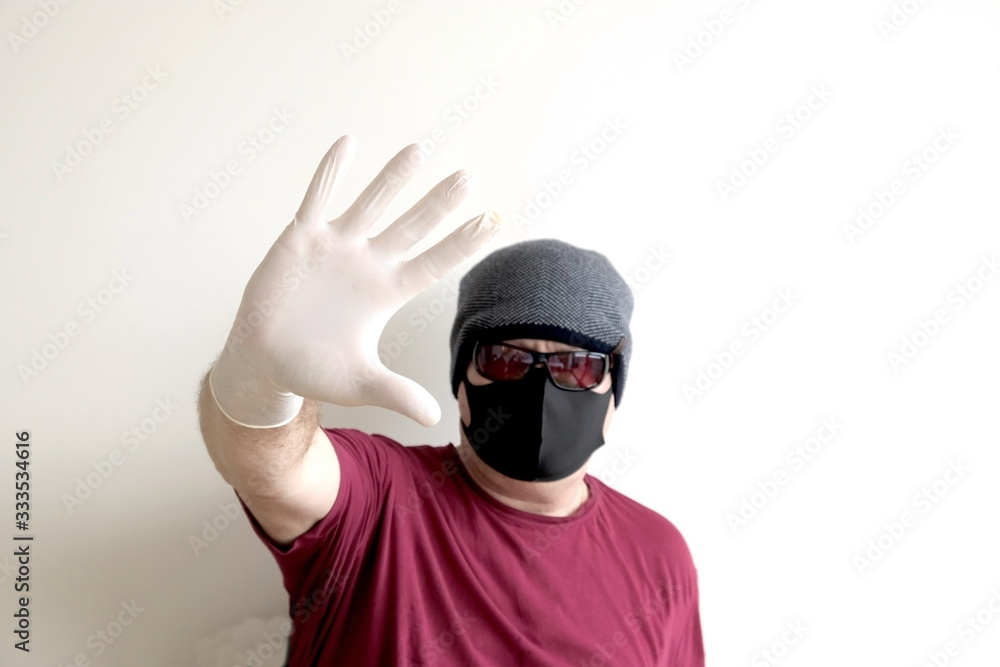 Obraz premium Portrait of a man protected from coronavirus. White, latex gloves. Hand protection against infections, viruses, germs. Isolation of the skin. On the face is a fabric mask. Glasses on the eyes. Symboli