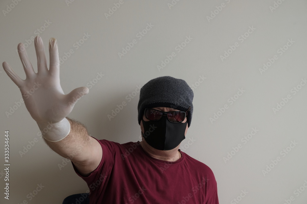 Portrait of a man protected from coronavirus. White, latex gloves. Hand protection against infections, viruses, germs. Isolation of the skin. On the face is a fabric mask. Glasses on the eyes. Symboli Portrait of a man protected from coronavirus. White, latex gloves. Hand protection against infections, viruses, germs. Isolation of the skin. On the face is a fabric mask. Glasses on the eyes. Symboli