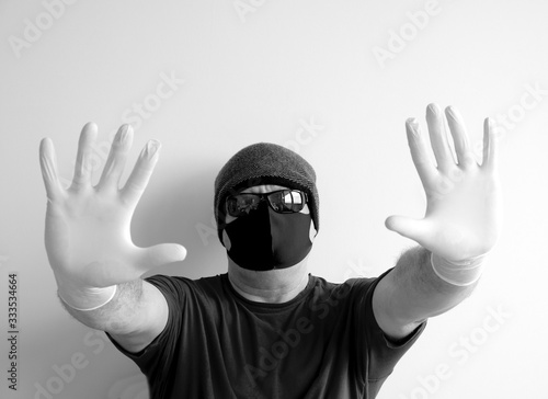 Portrait of a man protected from coronavirus. White, latex gloves. Hand protection against infections, viruses, germs. Isolation of the skin. On the face is a fabric mask. Glasses on the eyes. Symboli