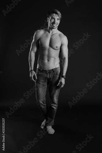black and white studio shoot of strong athletic man on dark background © zhenya popova