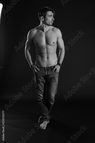 black and white studio shoot of strong athletic man on dark background © zhenya popova