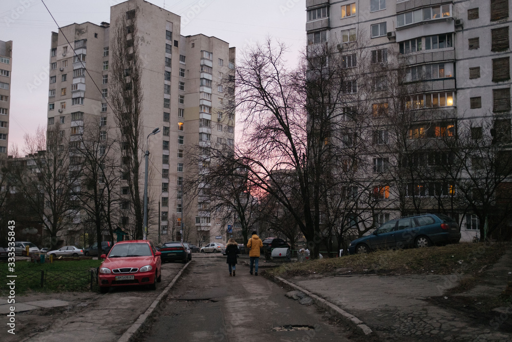 Obraz premium Two people walk down street in Kiev in pink sunset