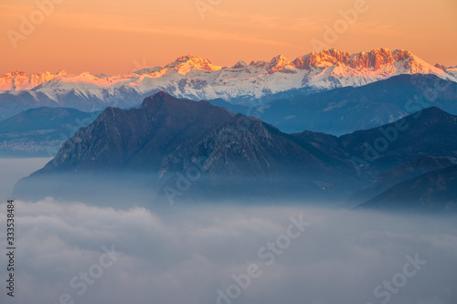 Orobie Alps in the morning with fog during winter season, Lombardy, Italy.