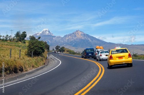 Highway south towards the Cotopaxi volcano, with traveling vehicles, on a sunny morning, Ecuador. © alanfalcony