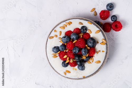 Tasty fresh blueberry raspberries yoghurt shake dessert in ceramic bowl standing on white table background.