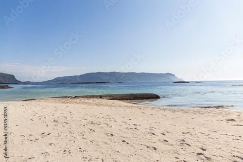 colorful contrasts, white sand beach, and crystal clear blue sea, mountains, green grass, some rocks and clear blue sky