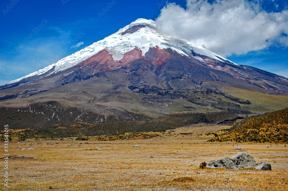 View of the Cotopaxi volcano on a sunny morning, with volcanic rocks in the foreground. Cotopaxi National Park, Ecuador