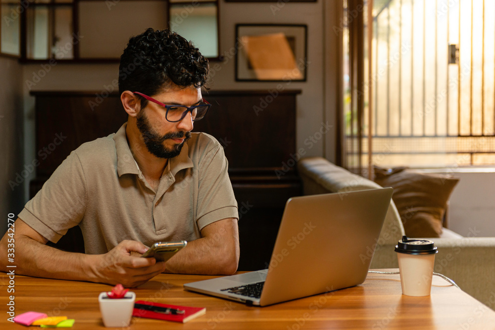 © Julio Ricco - Man holding cellphone at his workplace. Home office concept. © Julio Ricco - Man holding cellphone at his workplace. Home office concept.
