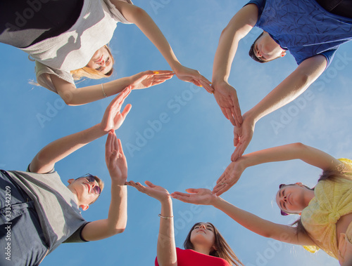 A group of friends makes a circle from the palms of their hands
