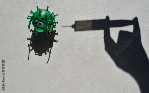 Conceptual shadow of a syringe injecting a vaccine to a green virus