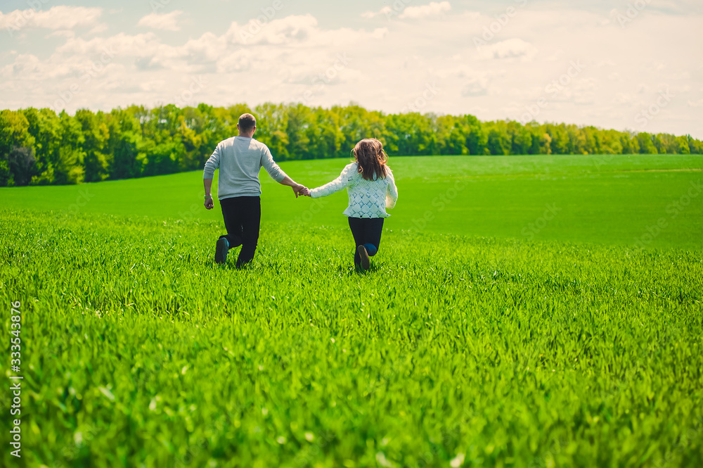 A guy with a girl running holding hands on a field of green grass A guy with a girl running holding hands on a field of green grass