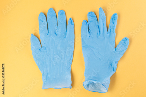 Two rubber gloves on a yellow background. Corona virus. Healthcare and medical concept. Close up view of medical protection of hands.