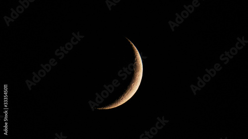 Fotografia, Obraz Astronomy: Tiny moon crescent full of small craters in the dark sky of the night