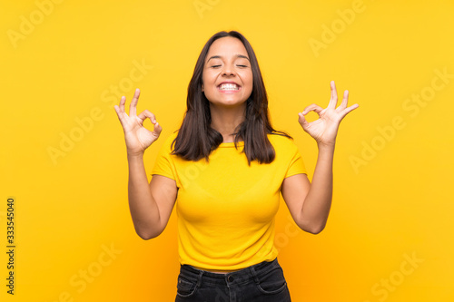 Young brunette girl over isolated background in zen pose