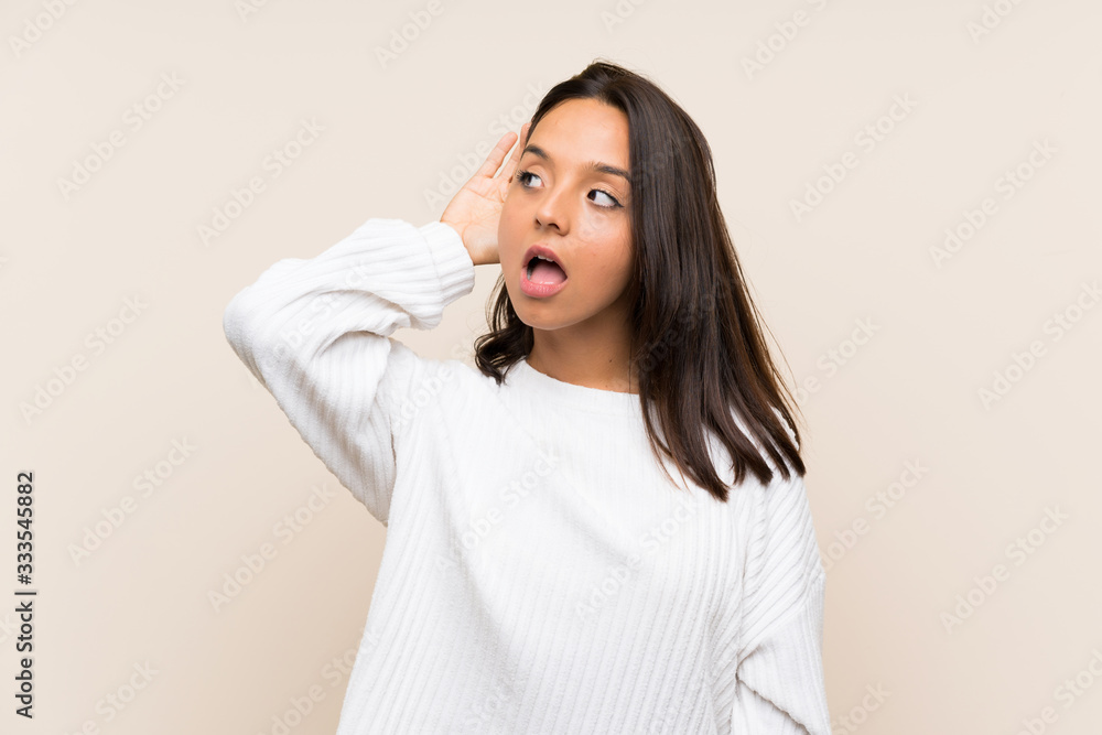 Young brunette woman with white sweater over isolated background listening something Young brunette woman with white sweater over isolated background listening something