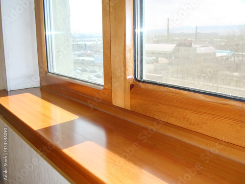 a window and a window sill from larch, from a natural tree, repair in a house installation of high-quality windows