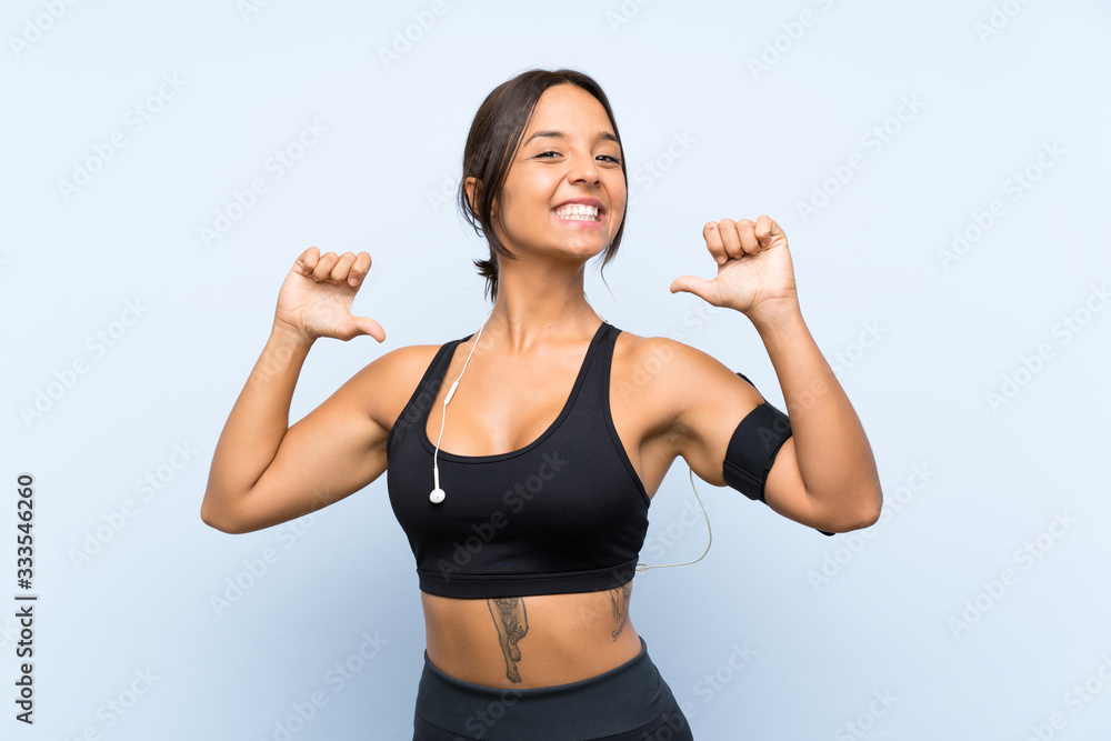 Young sport girl over isolated blue background proud and self-satisfied Young sport girl over isolated blue background proud and self-satisfied