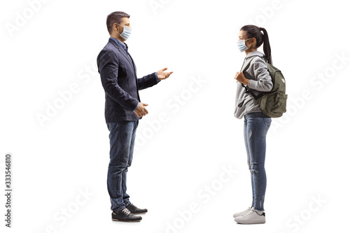 Young female student and a man with protective medical masks having a conversation