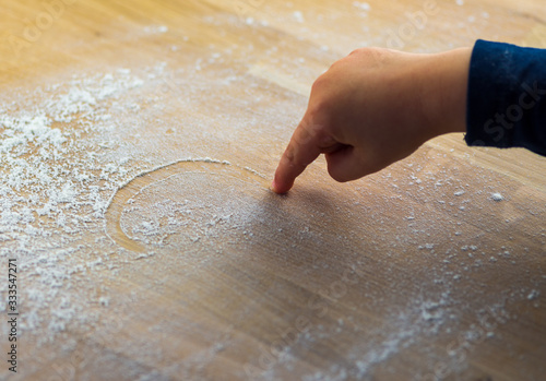 Ein kleines Mädchen möchte mit dem Finger ein Herz ins Mehl mahlen photo