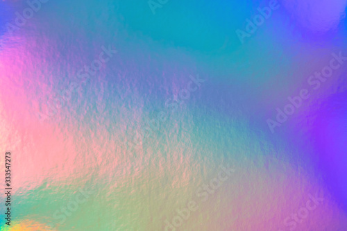 Abstract trendy rainbow holographic background in 80s style. Blurred texture in violet  pink and mint bright neon colors.