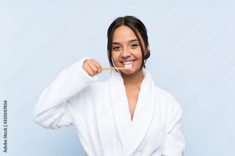 Young brunette girl in bathrobe with makeup over isolated blue background Young brunette girl in bathrobe with makeup over isolated blue background