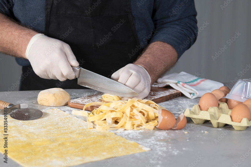 Chef cutting a roll of pasta into noodles Chef cutting a roll of pasta into noodles