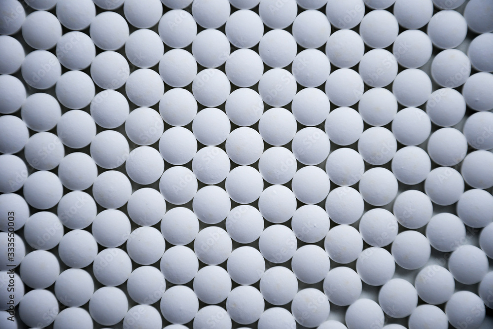 White tablets folded on a pharmaceutical factory production line close up pattern White tablets folded on a pharmaceutical factory production line close up pattern