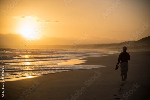silhouette of a woman walking on the beach at sunset