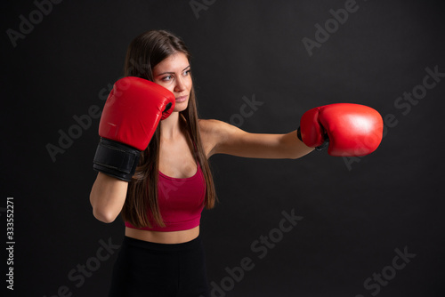 Young sport woman with boxing gloves over isolated black background