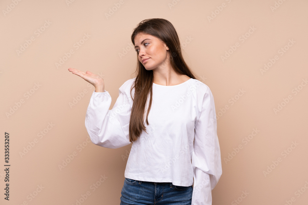 Young girl over isolated background holding copyspace with doubts Young girl over isolated background holding copyspace with doubts