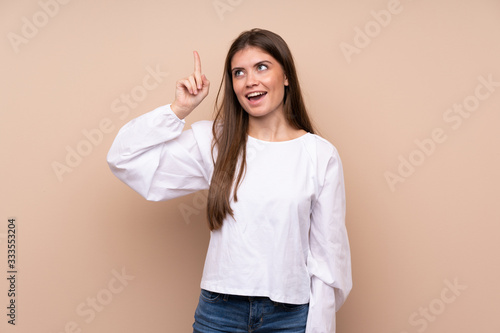 Young girl over isolated background intending to realizes the solution while lifting a finger up