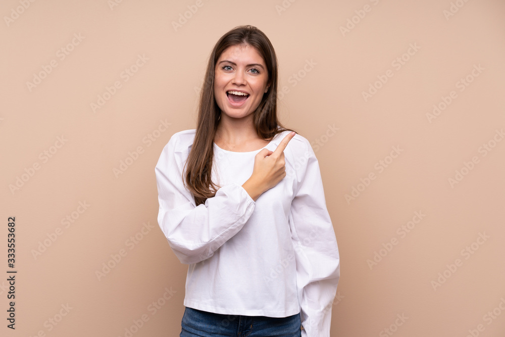 Young girl over isolated background surprised and pointing side Young girl over isolated background surprised and pointing side