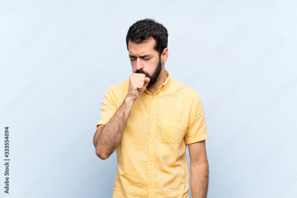 Young man with beard over isolated blue background is suffering with cough and feeling bad Young man with beard over isolated blue background is suffering with cough and feeling bad