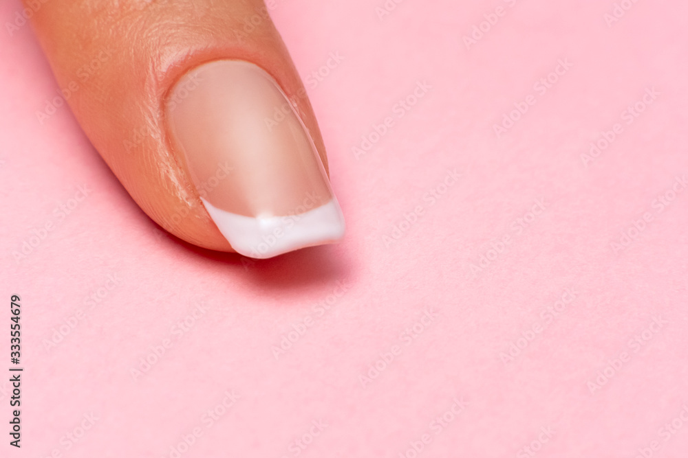 single female finger with a beautiful manicure on a pink background, close-up. clean healthy fingernails. copy space. place for text and logo. single female finger with a beautiful manicure on a pink background, close-up. clean healthy fingernails. copy space. place for text and logo.