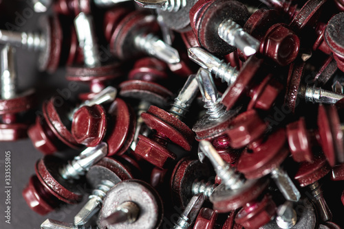 Top view of roofing screws background texture. Red roofing screws background. А bunch of self-tapping screws for fixing the roof with red heads