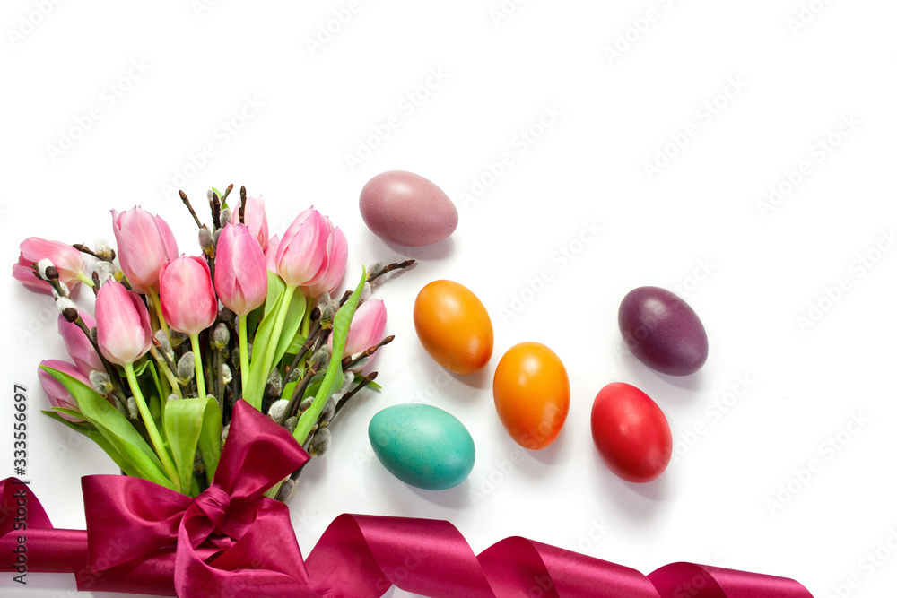 Obraz premium Easter background with pink tulips tied with a ribbon, catkins and colorful Easter eggs