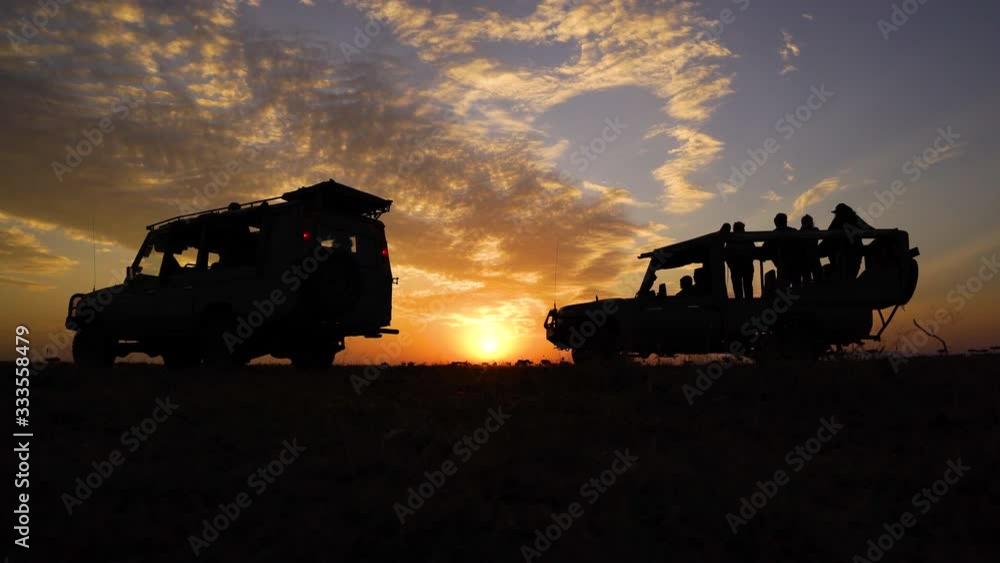 Safari cars in silhouette against the sunrise Safari cars in silhouette against the sunrise