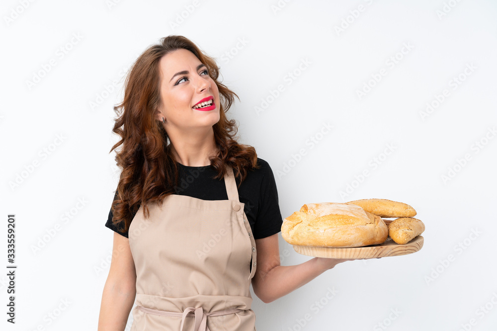 Woman in chef uniform. Female baker holding a table with several breads looking up while smiling Woman in chef uniform. Female baker holding a table with several breads looking up while smiling