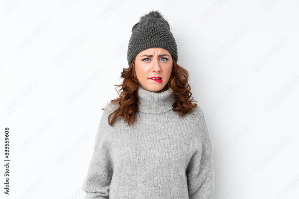 Young Russian woman with winter hat over isolated white background having doubts and with confuse face expression Young Russian woman with winter hat over isolated white background having doubts and with confuse face expression