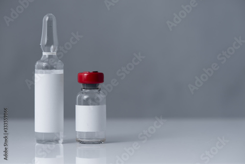 small bottle with a red cap and  Medical ampoule of various medicines on a white, gray background. Antibiotics, vaccines or other injectable drugs..