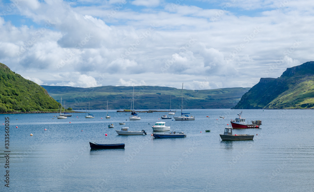 Fototapeta premium Portree harbor with small boats staying at anchors, Island of Skye, Hebrides archipelago, Scotland.