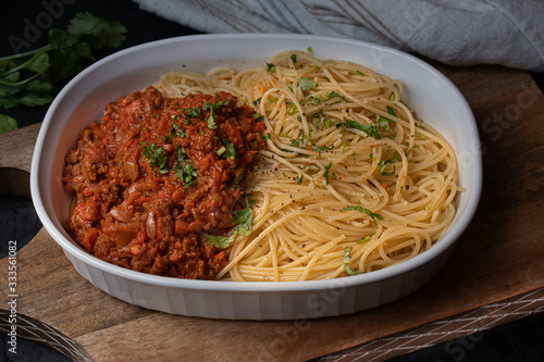 Vegan  seitan spaghetti bolognese in white serving dish