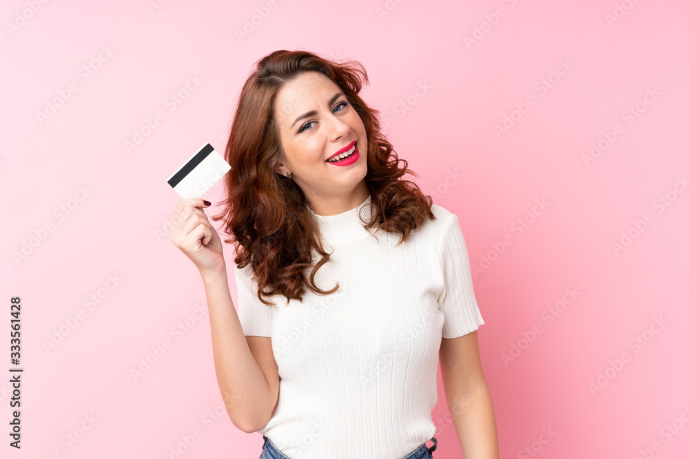 Young Russian woman over isolated pink background holding a credit card Young Russian woman over isolated pink background holding a credit card