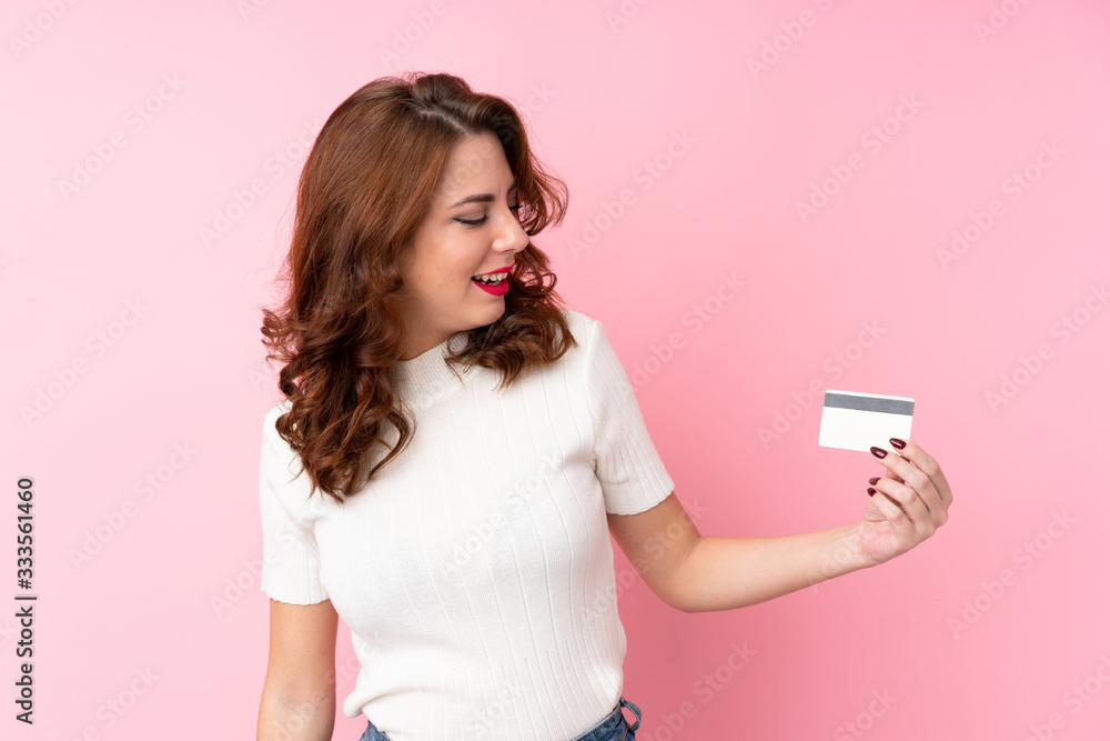 Young Russian woman over isolated pink background holding a credit card Young Russian woman over isolated pink background holding a credit card