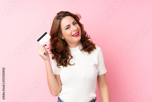 Young Russian woman over isolated pink background holding a credit card