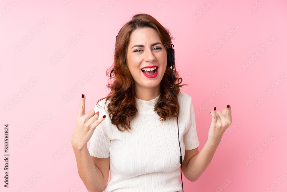 Young Russian woman over isolated pink background using the mobile with headphones and dancing Young Russian woman over isolated pink background using the mobile with headphones and dancing