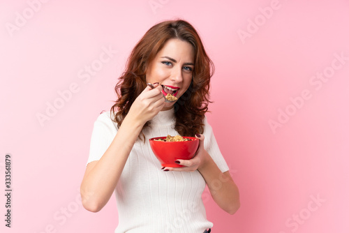 Young Russian woman over isolated pink background holding a bowl of cereals