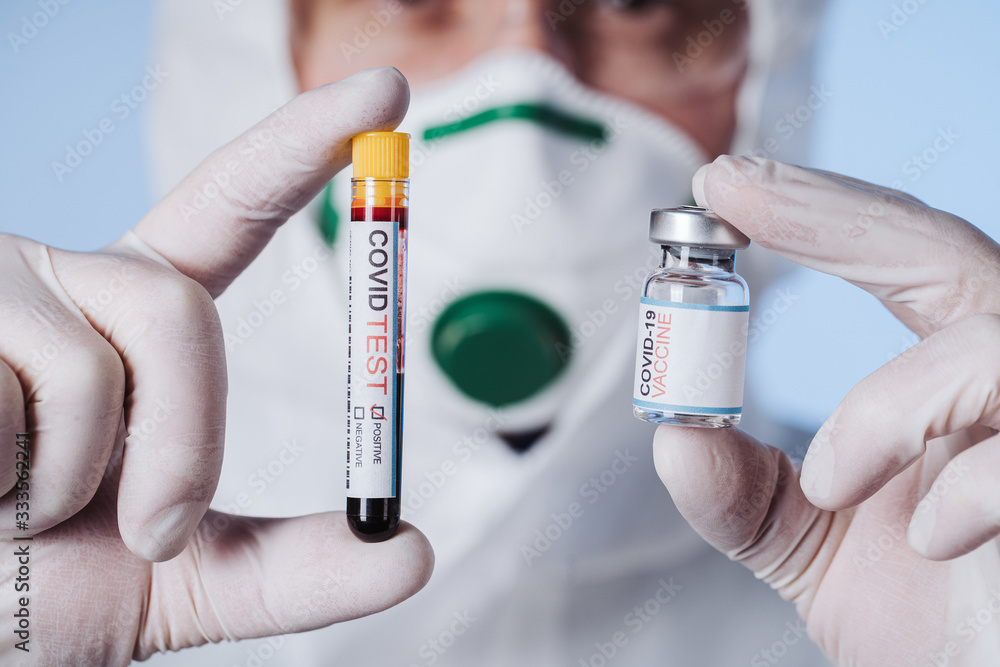 Lab with a tube of biological sample contaminated by Coronavirus with label Covid Test and glass bottle vaccine in laboratory. A breakthrough in the procedure. Vaccine research. Lab with a tube of biological sample contaminated by Coronavirus with label Covid Test and glass bottle vaccine in laboratory. A breakthrough in the procedure. Vaccine research.