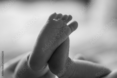 Newborn baby feet close up showing the creases and wrinkles on the soles of the feet. Black and white photo. Macro photo of tiny newborn baby feet.  