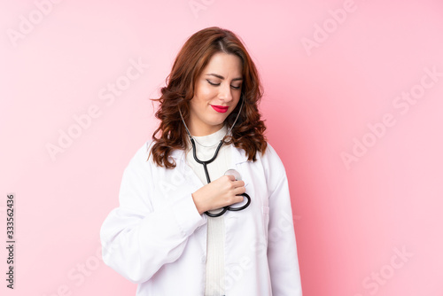 Young Russian woman over isolated pink background with doctor gown